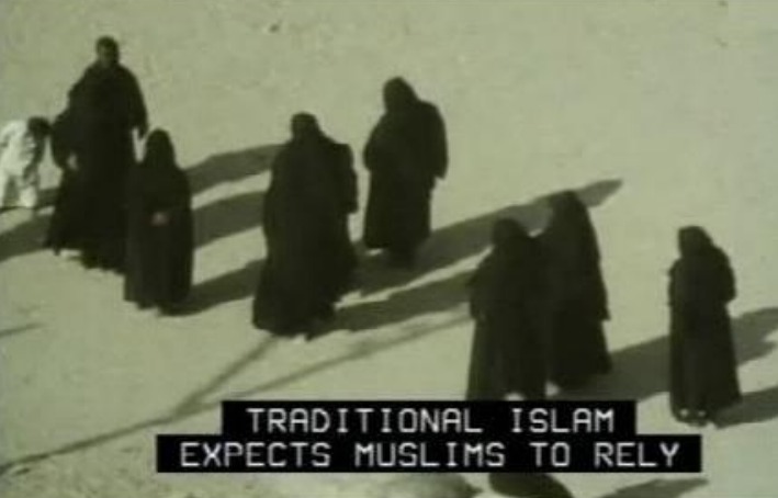 Video capture of several people wearing dark robes and head coverings walking on sand. Captions are all caps white letters over a black background that read Traditional Islam expects Muslims to rely.